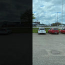 Venstre side er mørk, højre side viser klare biler, vej og bygninger under en skyet himmel.