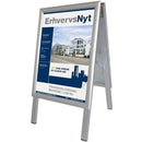 Alu Line A-skilt, A3 med plakat af bygning og teksten "ErhvervsNyt" i sølvramme.