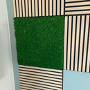 Mosbeklædt akustikpanel i grøn, omgivet af stribede paneler, del af modulært system, 60x60 cm.