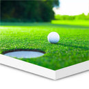 Golfbold tæt på hul på grøn mark, printet på 10 mm tyk tavle med hvid kant.