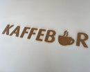 Bogstaverne "KAFFEBAR" i kork, hvor "A" i "BAR" er en kaffekop med damp.