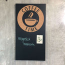 Sort opslagstavle med korkmotiv "Coffee Time", blågrøn kridttekst og kort fastgjort med magnet.
