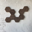 Mørke, sekskantede korkfliser arrangeret på en væg i et geometrisk mønster.