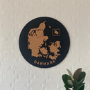 Rund vægpanel med Danmarkskort i kork og teksten "Danmark". Plante ses nedenfor.