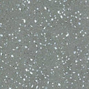 Grå overflade med terrazzo-lignende mønster, hvide, sorte og lysegrå spredte pletter.